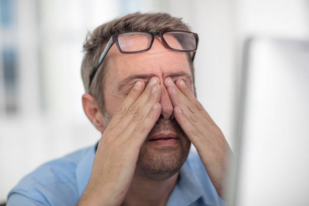 Homme souffrant de fatigue oculaire devant un écran d'ordinateur